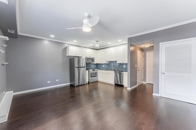 kitchen featuring appliances with stainless steel finishes, ceiling fan, a sink, ornamental molding, and tasteful backsplash