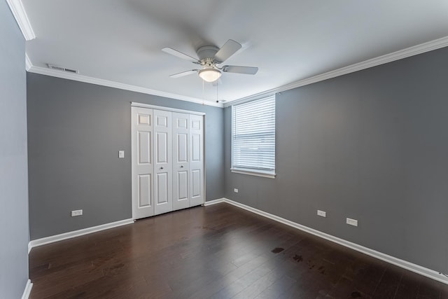 unfurnished bedroom featuring crown molding, baseboards, a closet, wood finished floors, and a ceiling fan