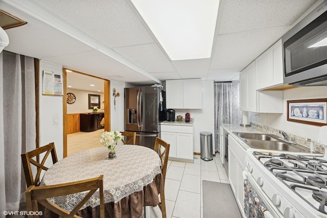 769 N Eastland St, Elmhurst, IL 60126 - kitchen featuring stainless steel appliances, a drop ceiling, white cabinets, a sink, and light tile patterned flooring