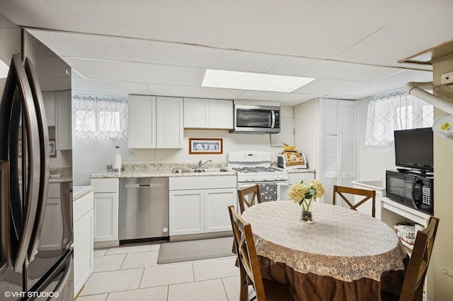 769 N Eastland St, Elmhurst, IL 60126 - kitchen with black appliances, a sink, a paneled ceiling, white cabinets, and light tile patterned floors
