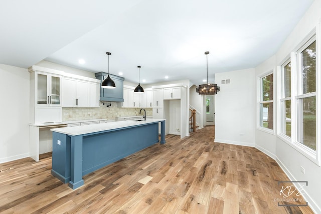 715 N Brainard St, Naperville, IL 60563 - kitchen featuring backsplash, white cabinetry, light countertops, a spacious island, and light wood finished floors