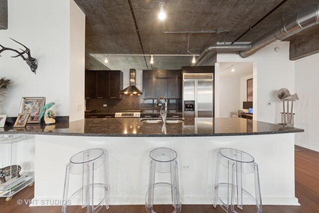 240 E Illinois St Unit 402, Chicago, IL 60611 - kitchen featuring stainless steel appliances, wall chimney exhaust hood, a sink, dark wood finished floors, and a breakfast bar area