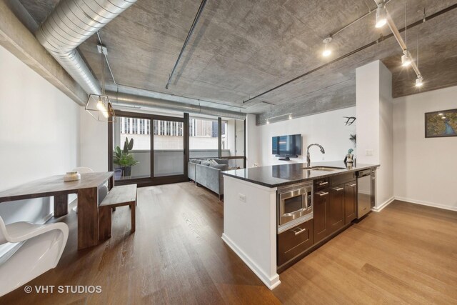240 E Illinois St Unit 402, Chicago, IL 60611 - kitchen featuring a sink, stainless steel appliances, wood finished floors, dark countertops, and open floor plan