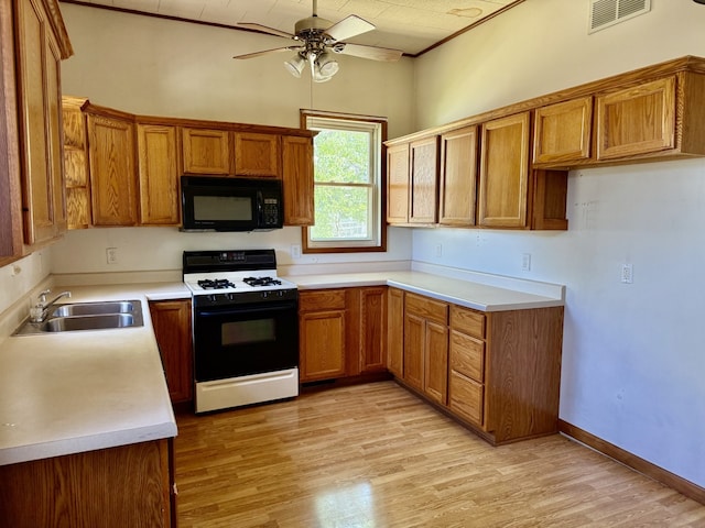 109 S Willow St, Toluca, IL 61369 - kitchen with black microwave, gas stove, a sink, brown cabinetry, and ceiling fan