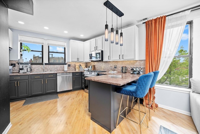 1637 W Columbia Ave Unit 3W, Chicago, IL 60626 - kitchen with appliances with stainless steel finishes, a sink, a peninsula, white cabinets, and a breakfast bar area