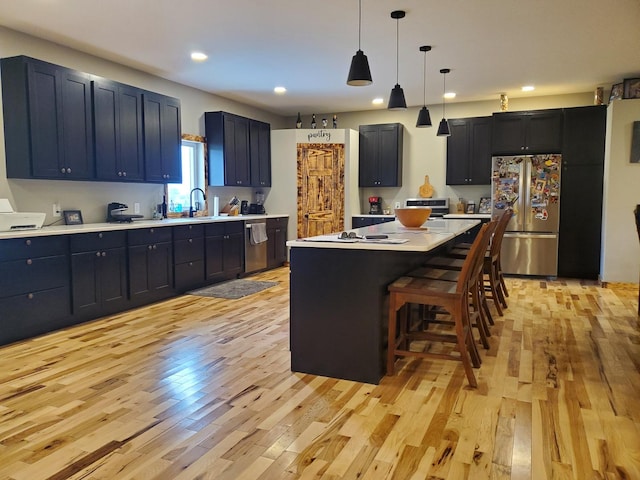 507 N Secor St, Gilman, IL 60938 - kitchen featuring appliances with stainless steel finishes, light wood-style flooring, light countertops, a kitchen breakfast bar, and recessed lighting