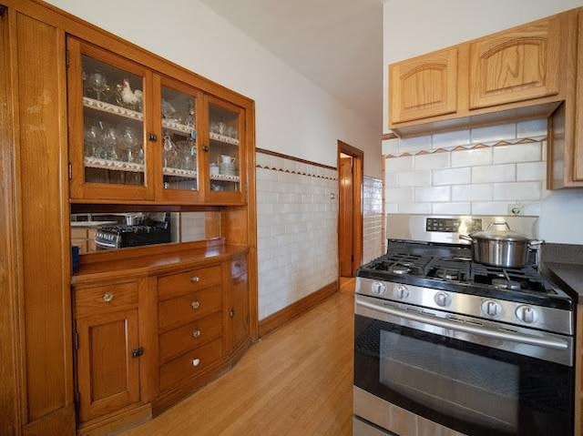 4912 S Komensky Ave, Chicago, IL 60632 - kitchen featuring stainless steel gas stove, light wood finished floors, glass insert cabinets, brown cabinetry, and decorative backsplash