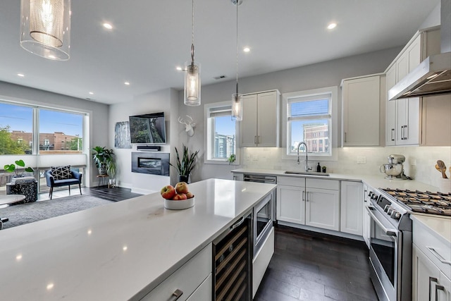 3224 N Elston Ave Unit 2S, Chicago, IL 60618 - kitchen with exhaust hood, stainless steel gas range, a sink, dark wood finished floors, and plenty of natural light