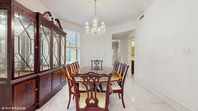 dining space with a chandelier, light tile patterned floors, and baseboards