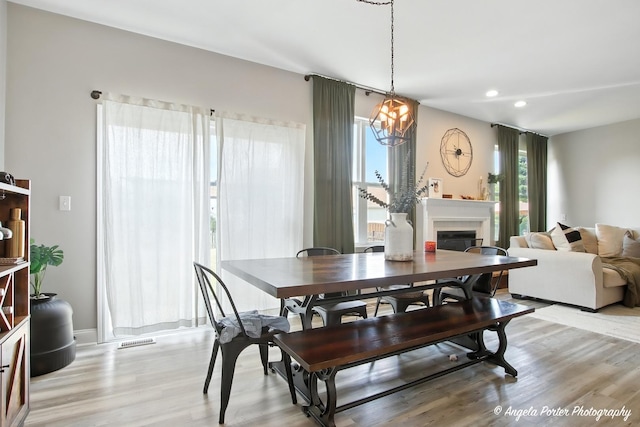 28912 Sawmill Ln, Lakemoor, IL 60051 - dining area with plenty of natural light, light wood finished floors, a chandelier, a glass covered fireplace, and recessed lighting
