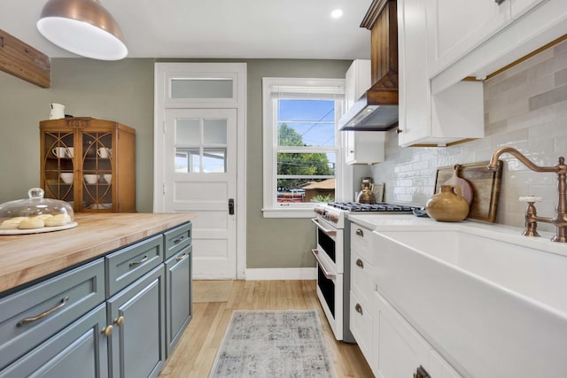 5912 W Grace St, Chicago, IL 60634 - kitchen featuring double oven range, wood counters, wall chimney exhaust hood, decorative backsplash, and light wood-type flooring