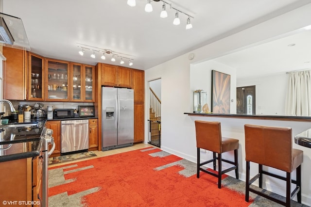 9351 Kostner Ave, Skokie, IL 60076 - kitchen with stainless steel appliances, brown cabinetry, rail lighting, dark countertops, and a sink