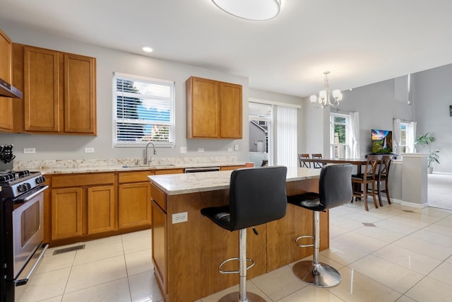 755 Rockhurst Rd, Bolingbrook, IL 60440 - kitchen with stainless steel range with gas stovetop, a chandelier, brown cabinetry, light tile patterned floors, and recessed lighting