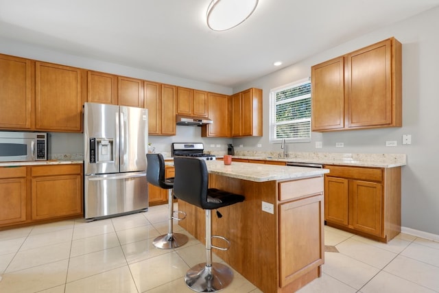 755 Rockhurst Rd, Bolingbrook, IL 60440 - kitchen with appliances with stainless steel finishes, under cabinet range hood, a kitchen island, light tile patterned floors, and light stone counters