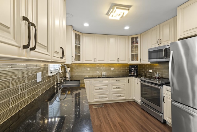 3907 New Haven Ave, Arlington Heights, IL 60004 - kitchen with appliances with stainless steel finishes, a sink, glass insert cabinets, backsplash, and dark stone countertops