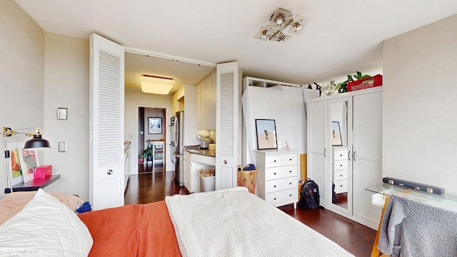 bedroom with dark wood-style floors and freestanding refrigerator