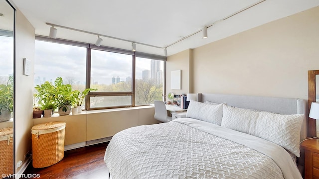 bedroom with track lighting and wood finished floors