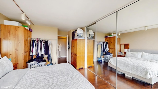 bedroom with rail lighting, dark wood-style flooring, and a closet