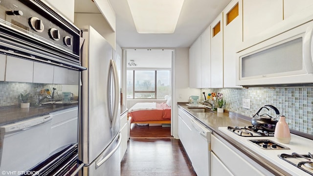 kitchen with white appliances, white cabinets, tasteful backsplash, and a sink
