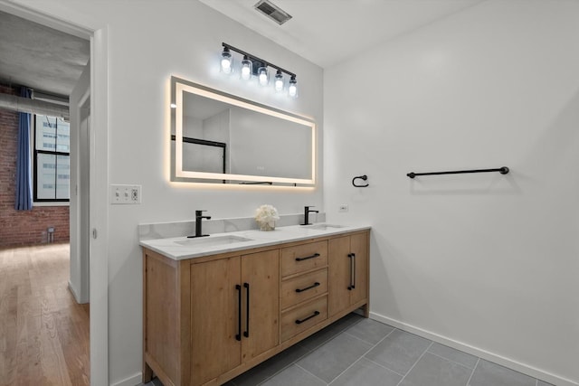 bathroom featuring baseboards, brick wall, and double vanity