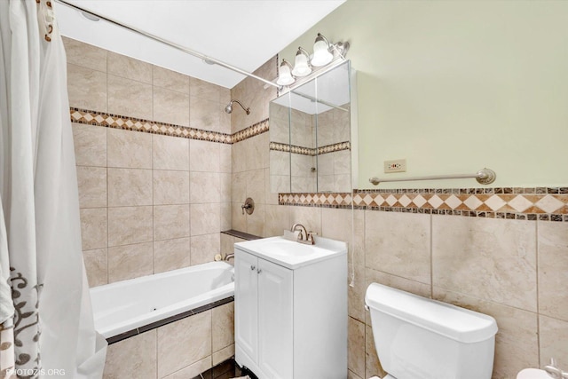 full bath with tile walls, tiled shower / bath combo, toilet, and vanity