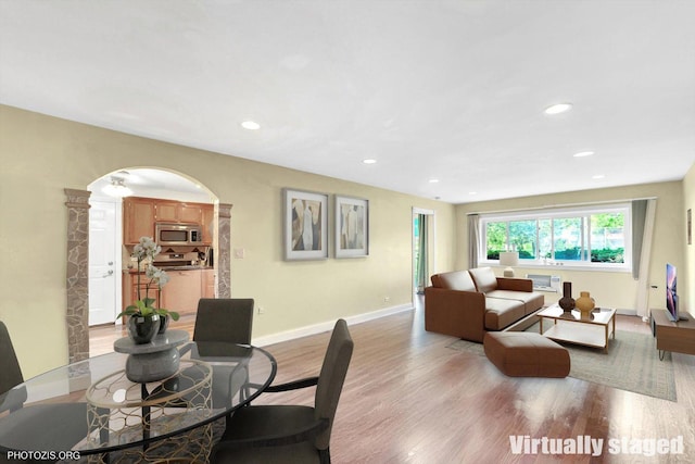 dining area featuring arched walkways, light wood-type flooring, baseboards, and recessed lighting