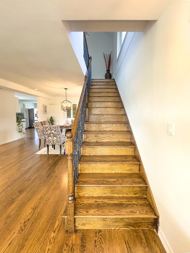 8024 N Odell Ave, Niles, IL 60714 - stairway with wood finished floors, a chandelier, and baseboards