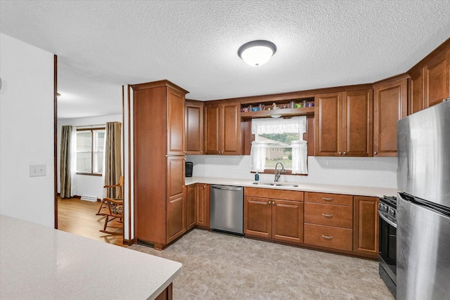 2908 Rolling Acres Dr, Champaign, IL 61822 - kitchen with appliances with stainless steel finishes, brown cabinetry, light countertops, plenty of natural light, and a textured ceiling