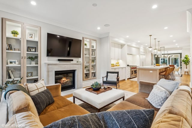 2034 N Mohawk St Unit 1, Chicago, IL 60614 - living area featuring light wood finished floors, a glass covered fireplace, recessed lighting, ornamental molding, and built in shelves