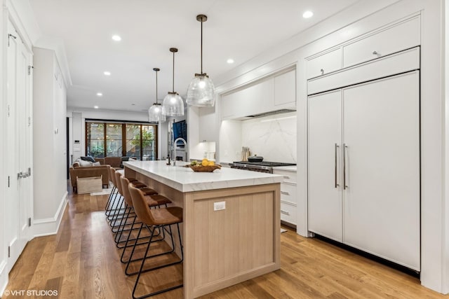 2034 N Mohawk St Unit 1, Chicago, IL 60614 - kitchen featuring paneled built in refrigerator, a breakfast bar, a kitchen island with sink, recessed lighting, and white cabinetry