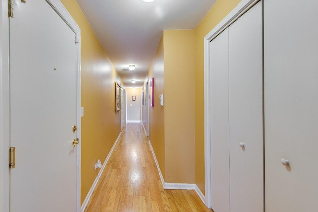 corridor with light wood finished floors and baseboards