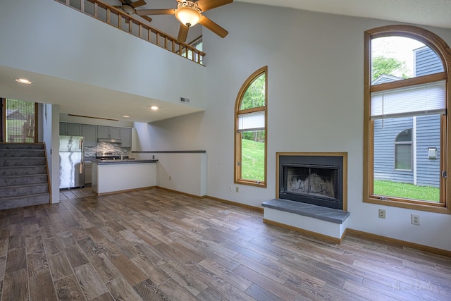 22 Valleywood Ln Unit 22, Galena, IL 61036 - unfurnished living room featuring plenty of natural light, a ceiling fan, stairs, dark wood-type flooring, and a high ceiling