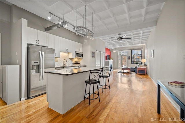 1307 S Wabash Ave Unit 402, Chicago, IL 60605 - kitchen with stainless steel appliances, light wood finished floors, a sink, coffered ceiling, and a breakfast bar