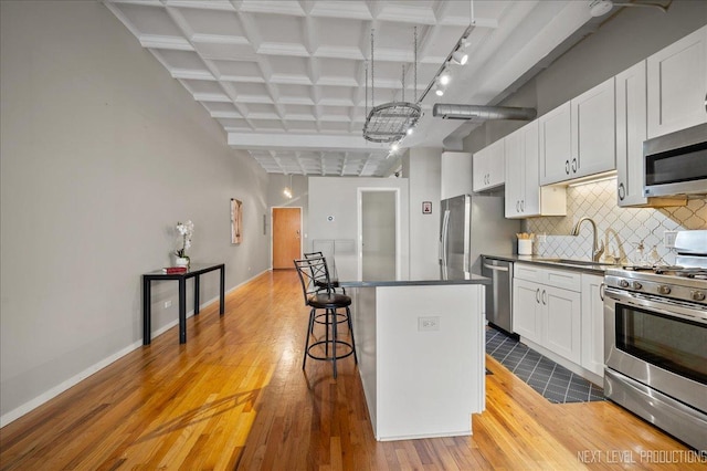 1307 S Wabash Ave Unit 402, Chicago, IL 60605 - kitchen with stainless steel appliances, a sink, a breakfast bar area, backsplash, and a center island