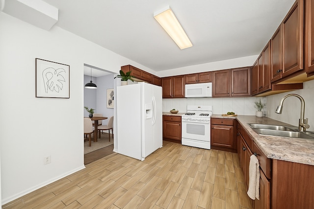 kitchen with white appliances, a sink, light wood-style floors, light countertops, and baseboards