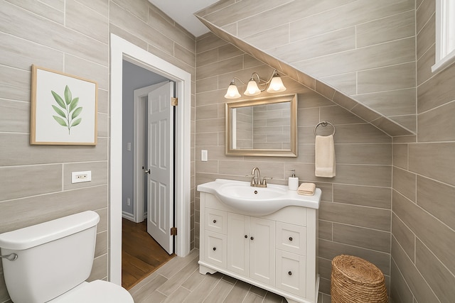 bathroom with tile walls, toilet, and vanity