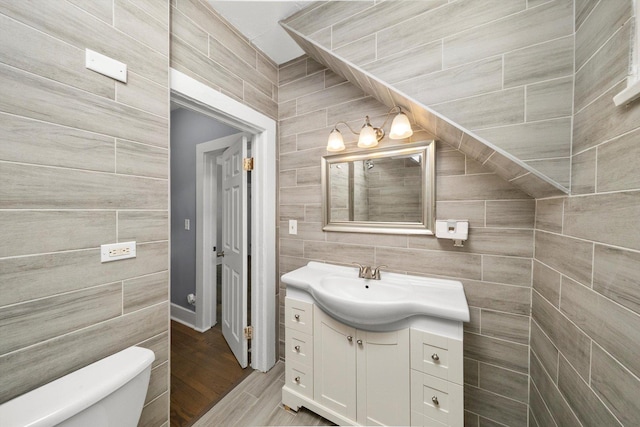 bathroom featuring tile walls, toilet, and vanity