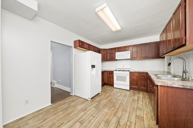 kitchen with white appliances, a sink, light wood finished floors, and light countertops