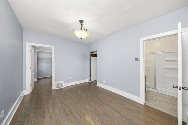 unfurnished bedroom with wood finished floors, a walk in closet, and baseboards