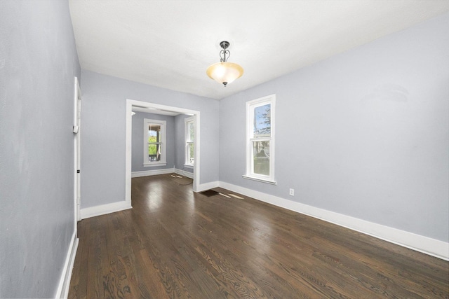 spare room with baseboards and dark wood-type flooring