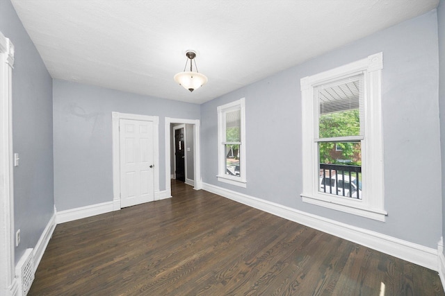 unfurnished room featuring plenty of natural light, baseboards, and dark wood-style flooring