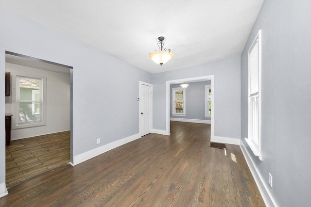 spare room featuring dark wood-type flooring and baseboards