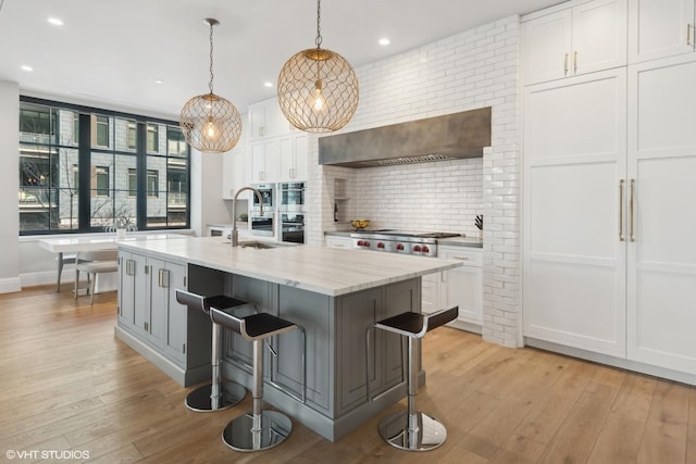 1109 W Washington Blvd Unit 2B, Chicago, IL 60607 - kitchen with white cabinetry, backsplash, light wood finished floors, a kitchen island with sink, and recessed lighting
