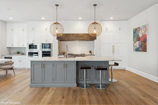 1109 W Washington Blvd Unit 2B, Chicago, IL 60607 - kitchen featuring white cabinetry, baseboards, decorative backsplash, a sink, and light wood-style flooring