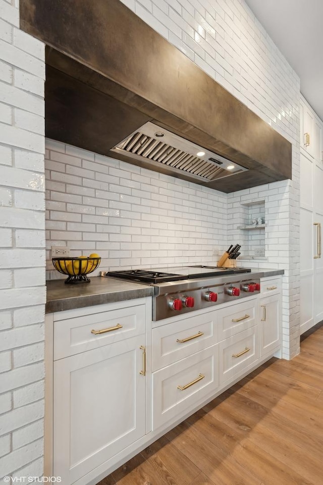 1109 W Washington Blvd Unit 2B, Chicago, IL 60607 - kitchen with stainless steel gas stovetop, white cabinets, decorative backsplash, dark countertops, and light wood finished floors