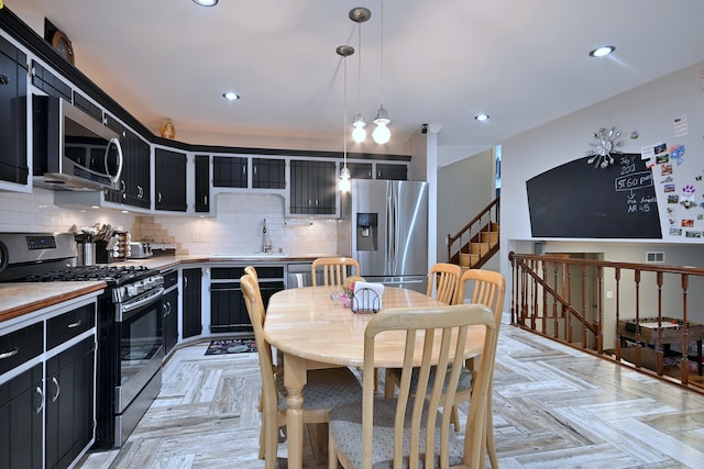 7701 New Castle Ave, Burbank, IL 60459 - kitchen with appliances with stainless steel finishes, dark cabinetry, a sink, decorative backsplash, and hanging light fixtures