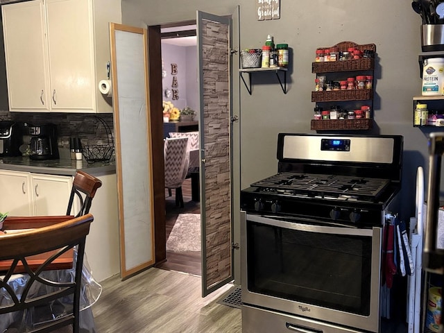 484 Hickory Pl, Elgin, IL 60120 - kitchen with stainless steel gas range oven, light wood finished floors, white cabinets, dark countertops, and tasteful backsplash