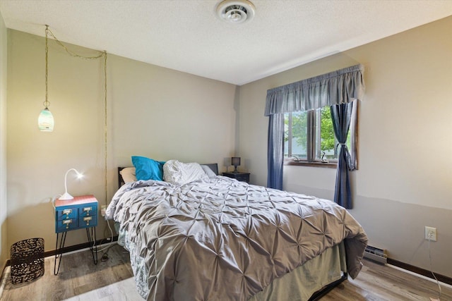 608 E Webster St, Polo, IL 61064 - bedroom with wood finished floors, baseboards, baseboard heating, and a textured ceiling