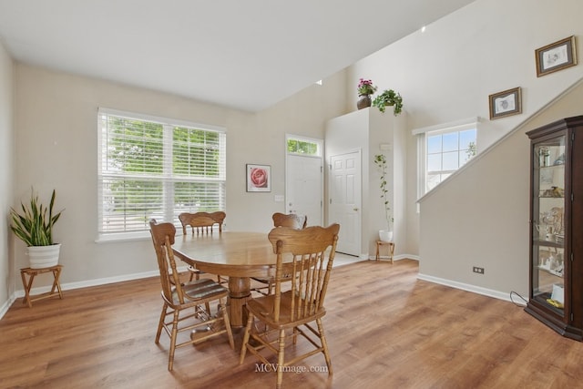 2295 Shiloh Dr, Aurora, IL 60503 - dining area featuring light wood finished floors, baseboards, stairs, and a towering ceiling