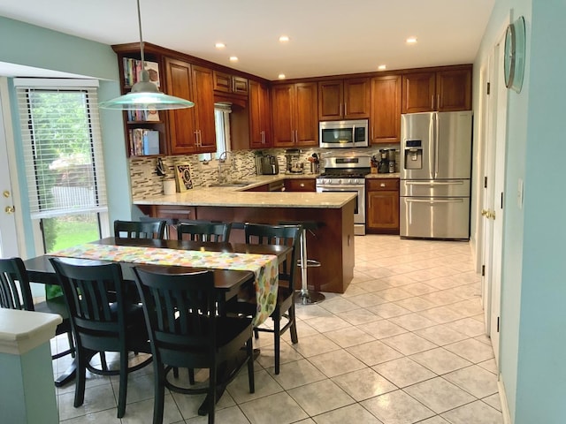 kitchen with appliances with stainless steel finishes, a sink, a peninsula, backsplash, and recessed lighting